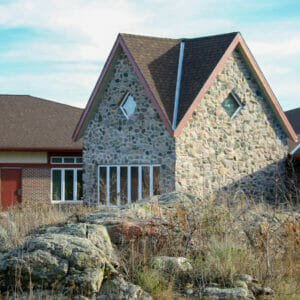 Exterior view of Project Turnabout with rock outcroppings in foreground, followed by two-story rock-clad building to the mid-ground and red-bricked building to the background.