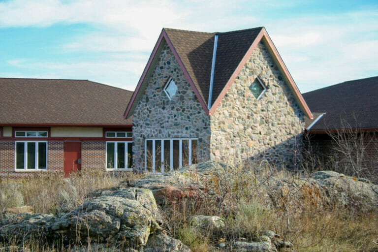 Exterior view of Project Turnabout with rock outcroppings in foreground, followed by two-story rock-clad building to the mid-ground and red-bricked building to the background.