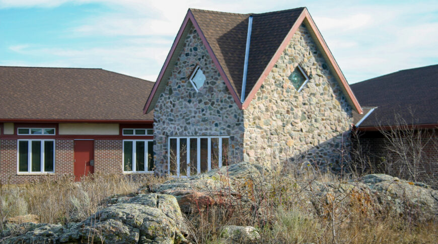 Exterior view of Project Turnabout with rock outcroppings in foreground, followed by two-story rock-clad building to the mid-ground and red-bricked building to the background.