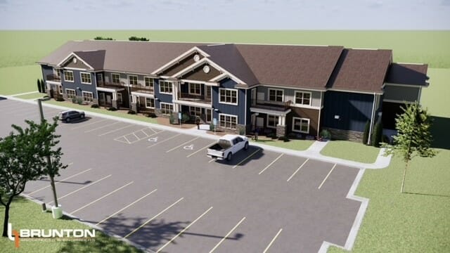 Exterior aerial rendering of a two-story apartment building with dark blue, beige, and brown siding with brick accents on first floor.