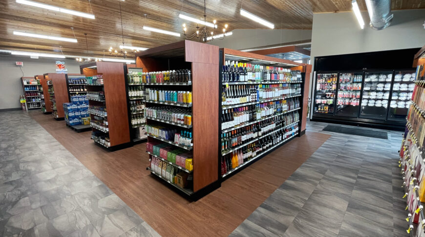 Interior view of Cenex C-Store liquor store with liquor isles down the center, coolers in the rear and vaulted pine planked ceiling overhead.