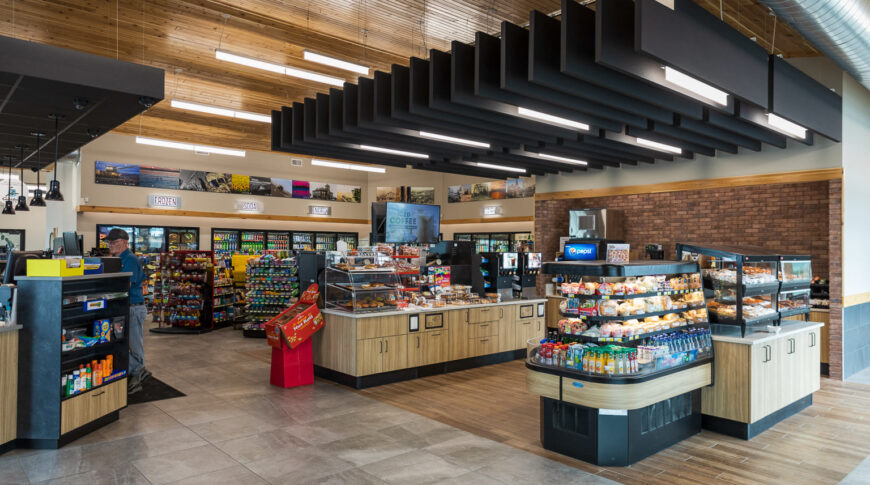 Cenex C-Store from front entrance view showcasing isles of freshly made sandwiches and lunch food, donut and coffee kiosks, and snacks and coolers to the background with cashier's station to top left.