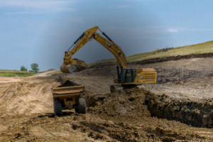 Dirt civil worksite with yellow excavator loading dirt into a haul truck.