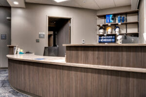 Curved reception desk with two levels with computer stations behind it and a wall of merchandise racks to the back.