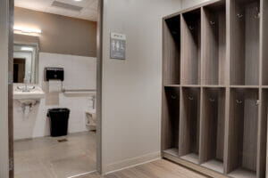 Open double-stacked locker spaces next to bathroom opening where we can see a sink and part of a toilet.