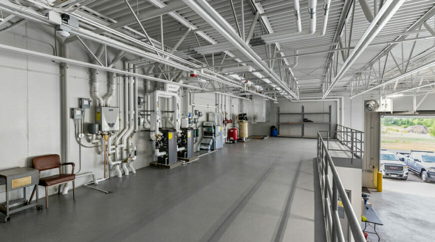 Second floor mezzanine with utility and HVAC panels, gray floor with gray railing overlooking truck bay.