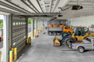 Upper deck view of truck garage with open bays to the right and trucks in the foreground.