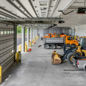 Upper deck view of truck garage with open bays to the right and trucks in the foreground.
