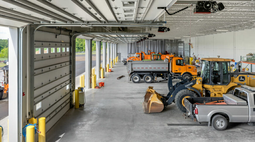 Upper deck view of truck garage with open bays to the right and trucks in the foreground.