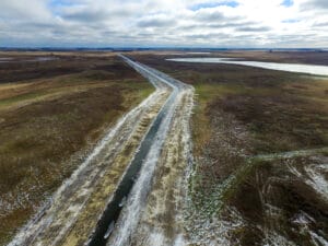 View from the air of a newly excavated and regraded drainage ditch running through pasture and farmland.