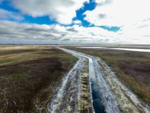 View from the air of a newly excavated and regraded drainage ditch running through pasture and farmland.