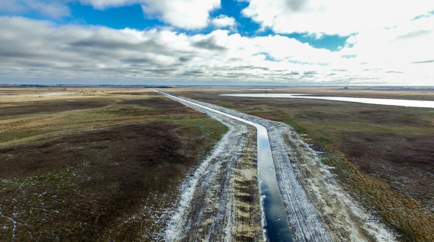 View from the air of a newly excavated and regraded drainage ditch running through pasture and farmland.