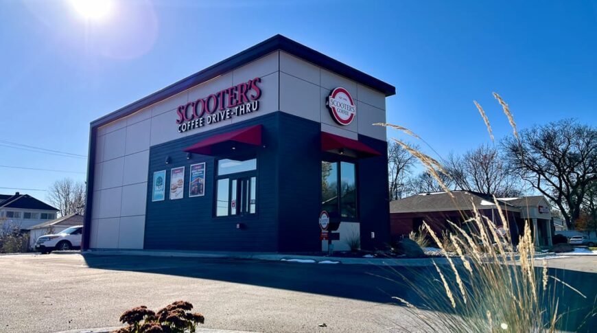 Coffee drive-thru building with taupe, black, and red facade on a sunny fall day.