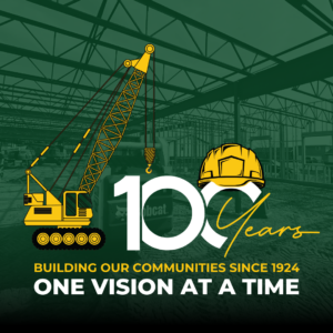 "100-Years" logo with construction crane and yellow hard hat icons amidst the logo. Image of construction site with metal and wood framing in the background.