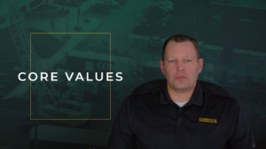White middle aged male with blue eyes and short brown hair wearing black polo. Green construction photo overlayed background with the words "Core Values."