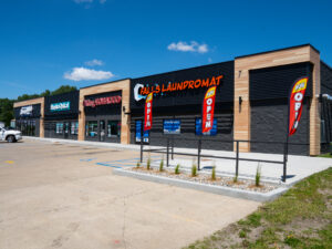 Exterior view of a newly constructed strip mall with black brick and light wood paneling accents.