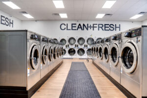 Looking down aisle of washing machines on each side with a row of double stacked machine on the back wall.