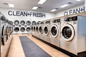 Looking down aisle of washing machines on each side with a row of double stacked machine on the back wall.