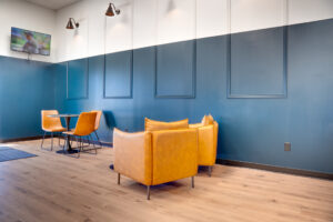 Lounge area of laundromat with table and chairs and tv in the background.