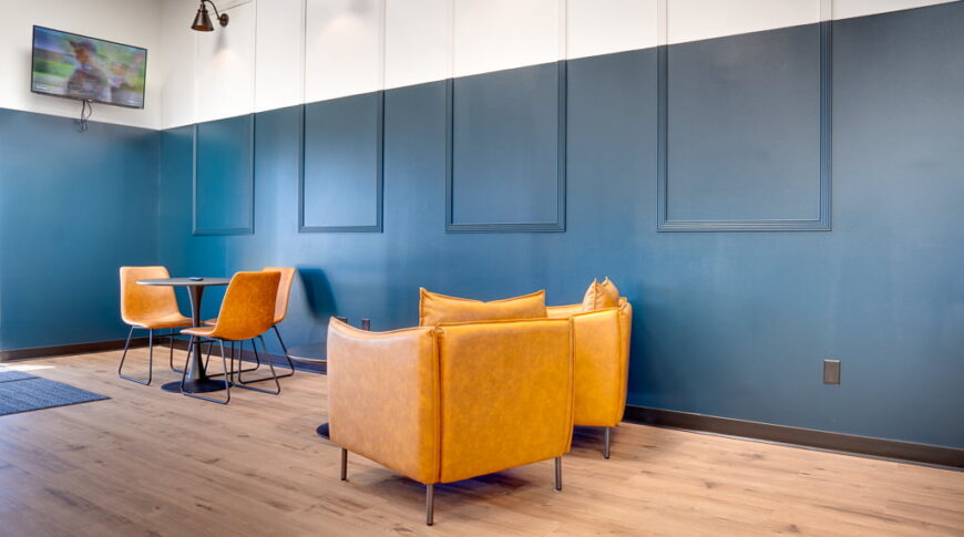 Lounge area of laundromat with table and chairs and tv in the background.