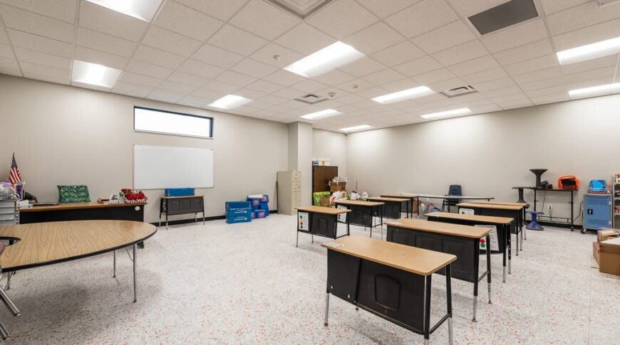 Brand new classroom building with modern flooring and tiled ceiling and beige walls.