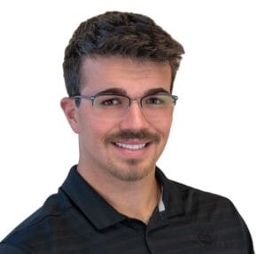 Young man in twenties with short scruffy dark brown hair, brown eyes, and goatee with glasses and black polo striped shirt.