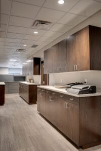 Dark-stained upper and lower cabinetry that is bar-height lined down the office hallway.