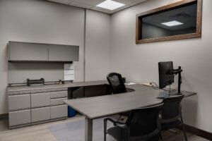 Office with gray walls and cabinetry with u-shaped desk in the middle.