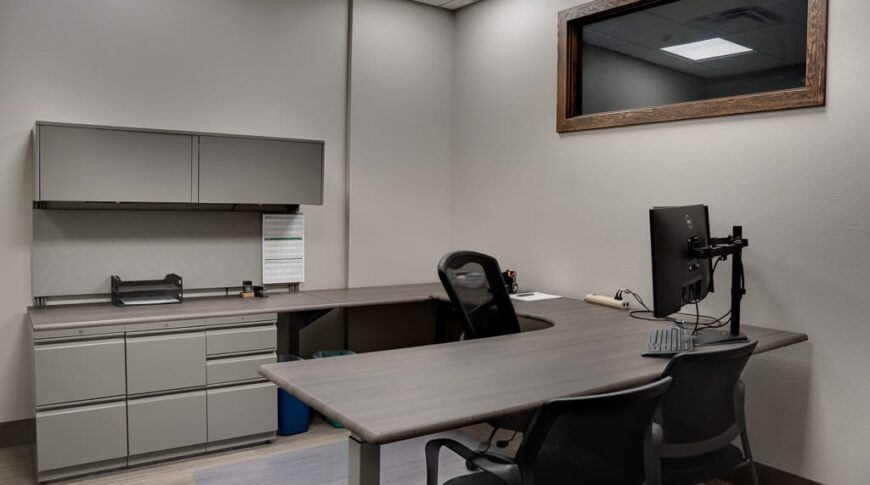 Office with gray walls and cabinetry with u-shaped desk in the middle.