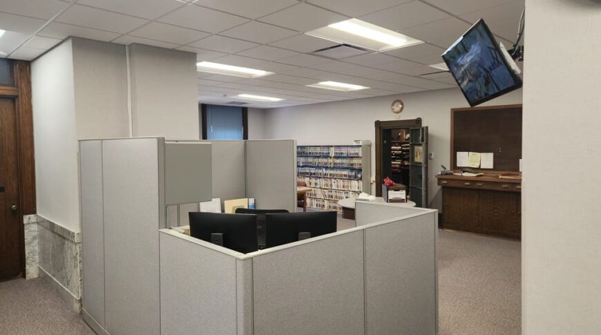 Courthouse office cubicle area with security screen on upper right wall.