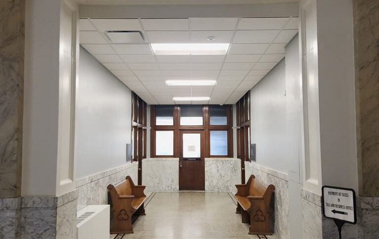 Grand courthouse corridor with stone wall trim and flooring.