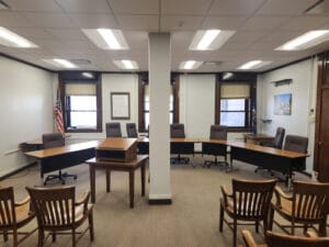 Informal courtroom with panel of desks in the front and audience seating in back.