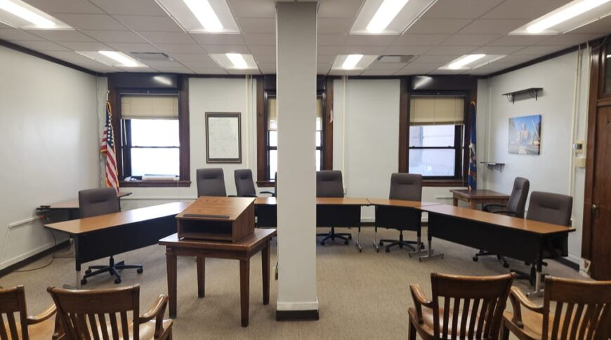 Informal courtroom with panel of desks in the front and audience seating in back.