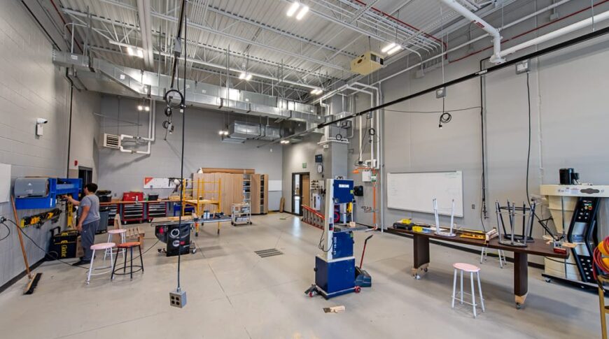 Large workshop with tall ceilings of exposed metal trusses at Dunseith CTE center. Photo by Icon Architectural Group.