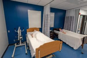 Medical manikin in hospital beds divided by curtain to simulate real hospital room at Dunseith CTE Center. Photo by Icon Architectural Group.