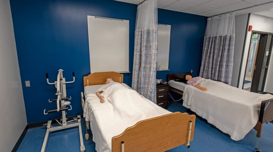 Medical manikin in hospital beds divided by curtain to simulate real hospital room at Dunseith CTE Center. Photo by Icon Architectural Group.