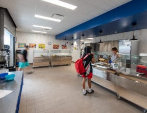 Student with red backpack walking through cafeteria line at Dunseith CTE Center. Photo by Icon Architectural Group.