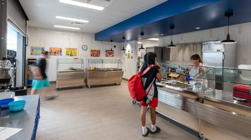 Student with red backpack walking through cafeteria line at Dunseith CTE Center. Photo by Icon Architectural Group.