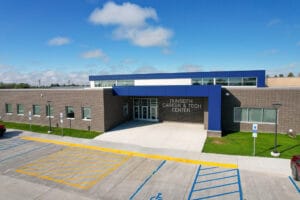 Aerial view of one-story CTE center with dark brown brick and blue accented panels. Photo by Icon Architectural Group.