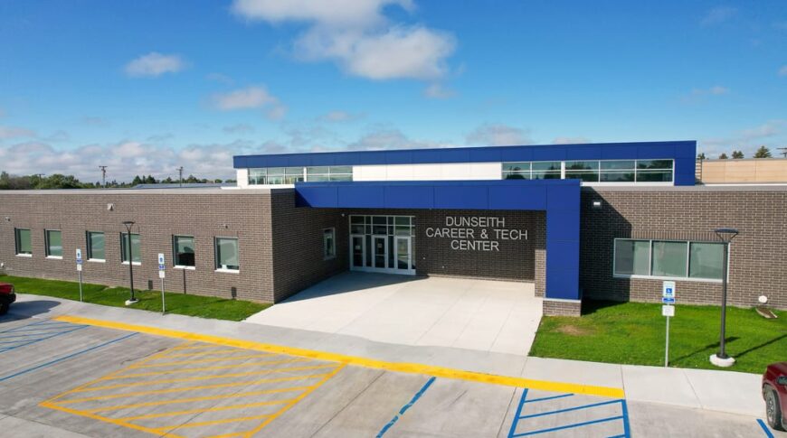 Aerial view of one-story CTE center with dark brown brick and blue accented panels. Photo by Icon Architectural Group.