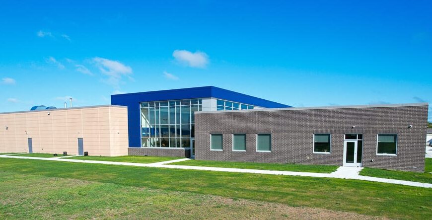 Exterior aerial view of a CTE center with brown brick section on the right, blue accented facade with full windows in the center, and beige precast concrete to the left. Photo by Icon Architectural Group.
