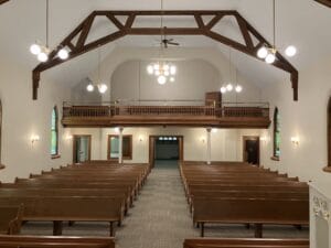 After view from the pulpit looking over rows of pews and choir loft remodeled with new flooring and paint.