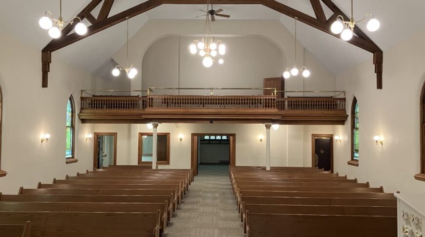 After view from the pulpit looking over rows of pews and choir loft remodeled with new flooring and paint.