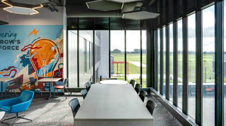 Second-floor den area with graphic wall element to back left, and bar-height seating station with stools surrounded on two sides by floor to ceiling windows.