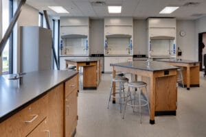 Science lab with lab tables and stools and equipment to the back wall.