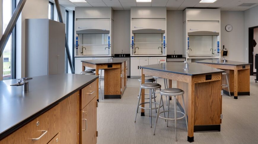 Science lab with lab tables and stools and equipment to the back wall.