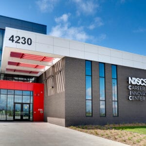 Exterior entrance of NDSCS Career Innovation Center building. A mix of brick facade to the left, and bright red paneling to the right.
