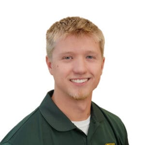 Young man with spikey light blonde hair and light skin with blue eyes wearing green polo and white undershirt on white background.
