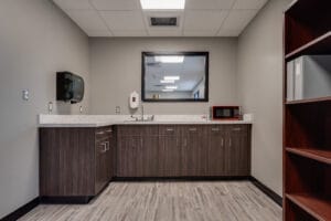 Breakroom kitchenette with sink and microwave and some dark walnut laminated cabinets.