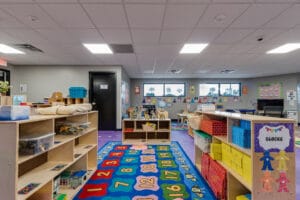 Kids playroom with waist-height storage shelves on either side, a brightly-colored numbers rug underneath and toys all around.